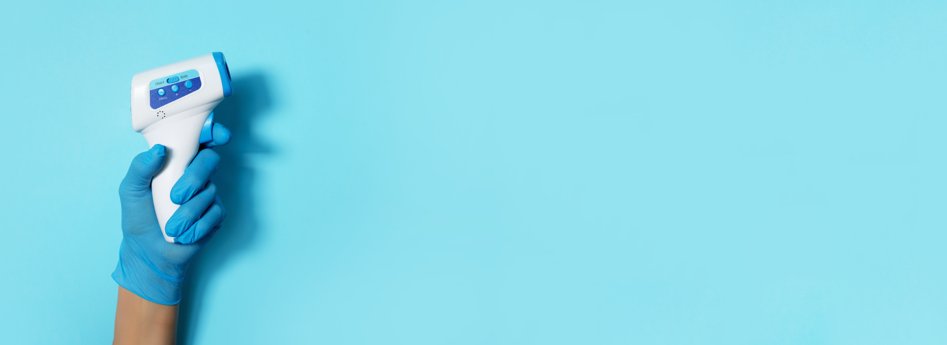 Infrared thermometer held up against blue background