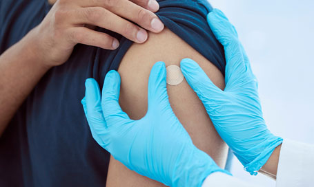 Apply small round plaster to mans arm