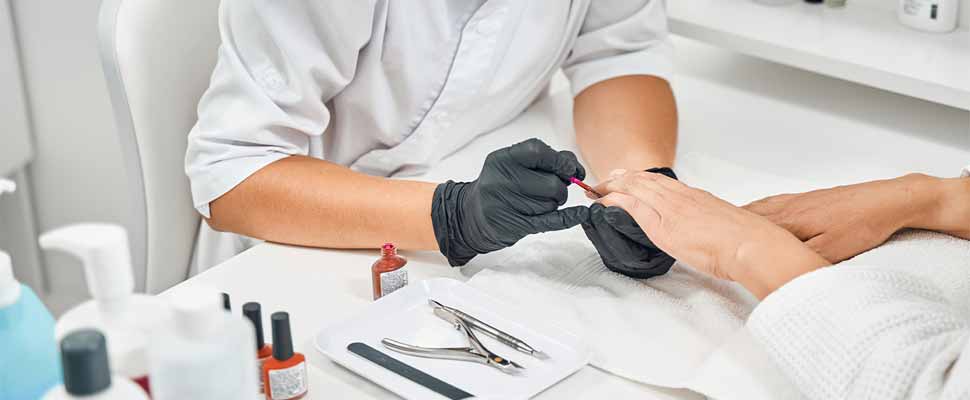 Attentive beautician applies new layer of nail polish