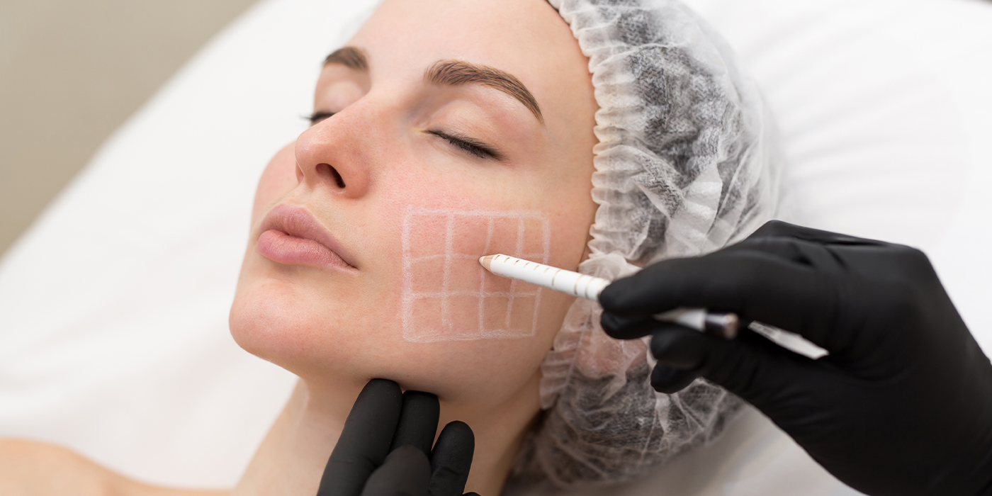 Beautician draws the contours of a white pencil on the face of the patient
