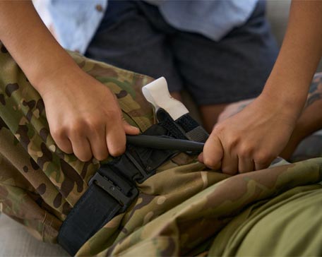 Boy turning handle to tighten tourniquet on army man leg