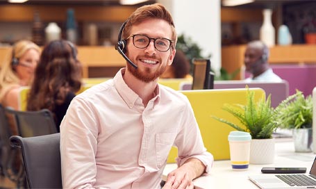 Portrait Of Businessman Wearing Headset Talking To Caller In Customer Services Centre