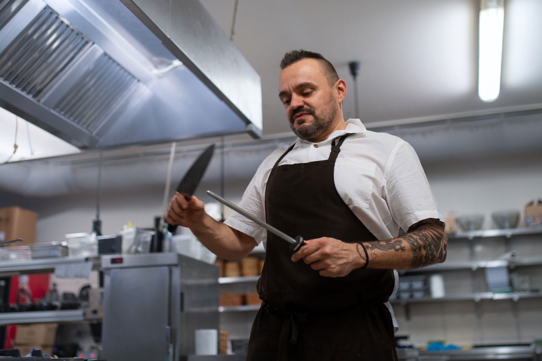 Low angle view of professional chef sharpening knife in restaurant kitchen