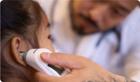 doctor otolaryngologist looks through otoscope the ears of a little girl
