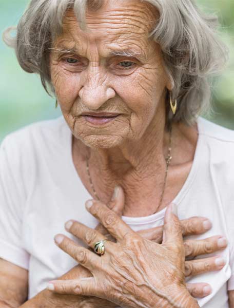 Elderly woman suffering cardiac arrest clutching chest
