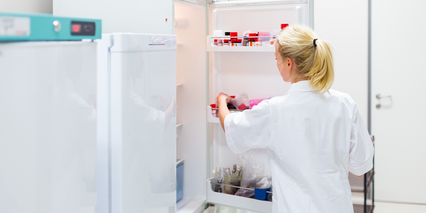 Female researcher storing chemical solutions in refrigeration cabinet