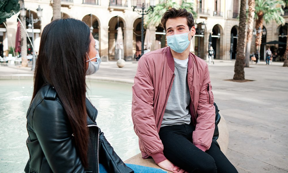 Friends wearing a face mask and talking outdoors