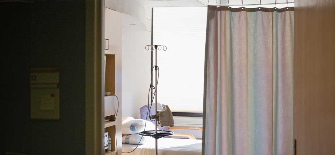 Hospital room with bed and privacy curtain.