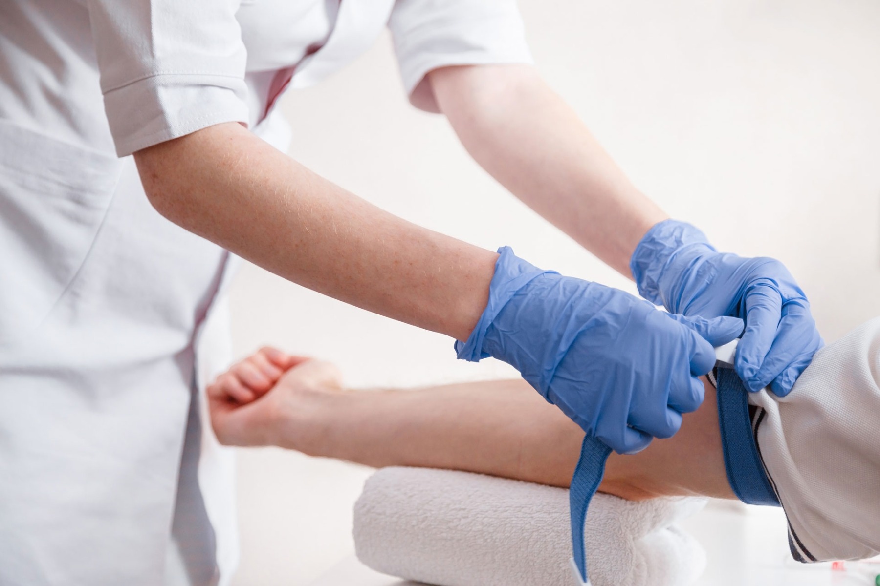 Nurse fastening medical tourniquet on casualty's arm