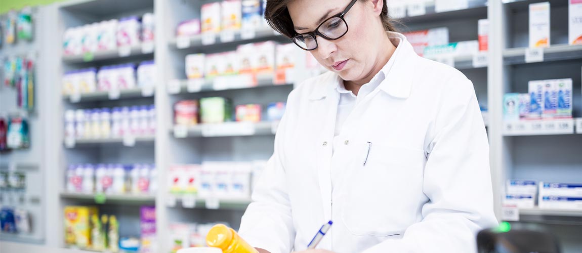 Pharmacist with medicine at counter in pharmacy