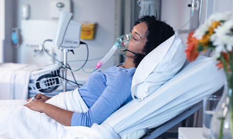 Sleeping female patient in hospital bed with oxygen ventilator