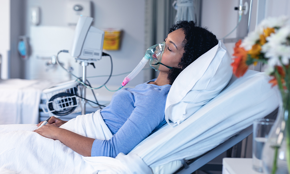 Sleeping female patient in hospital bed with oxygen ventilator
