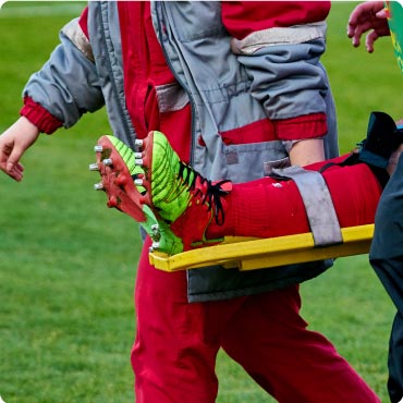 Close up of paramedics carrying footballer off the pitch on a stretcher