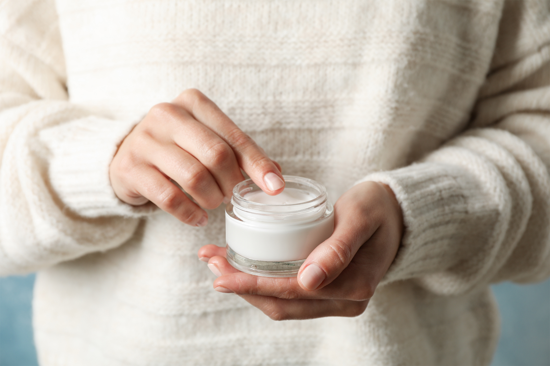 woman holding glass jar of ointment