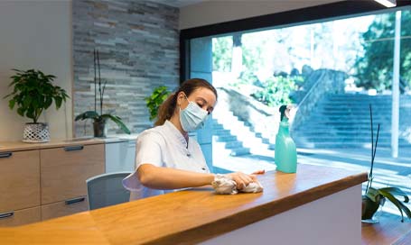 Young woman cleaning reception of spa center