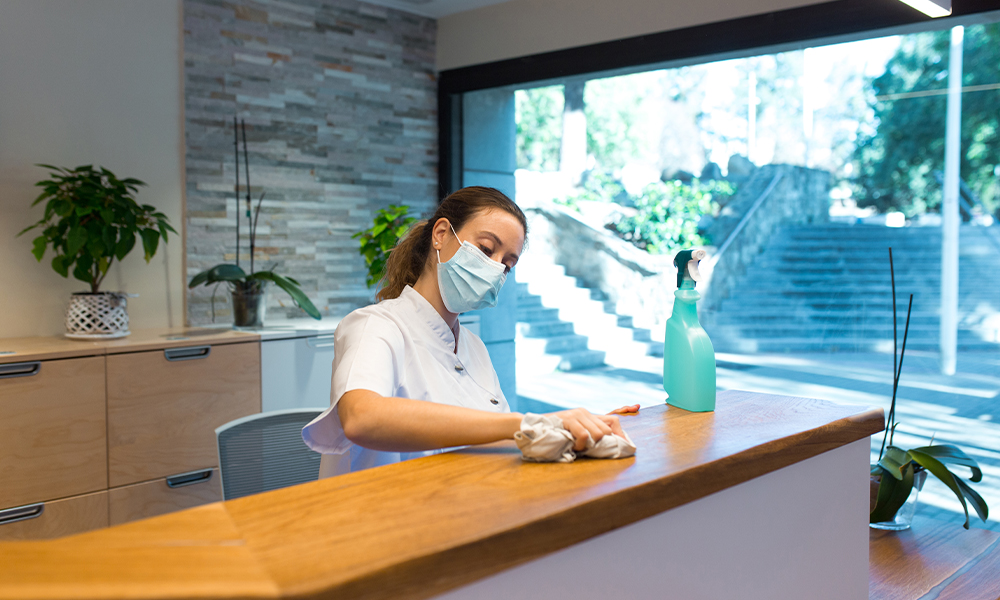 Young woman cleaning reception of spa center