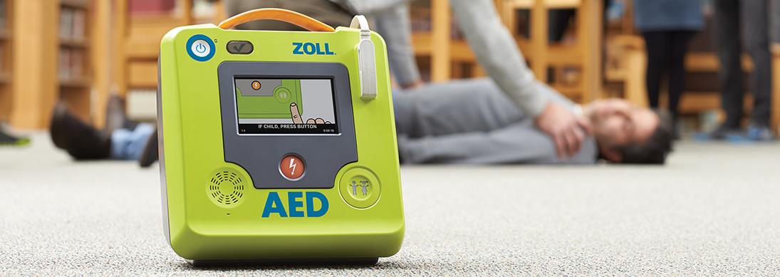 ZOLL Defibrilator on the floor in front of a scene where someone has collapsed