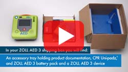 Unboxing of the ZOLL AED 3 showing device, accessory tray, CPR Uni-padz, battery pack, and documentation included in the shipping box.