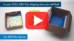Unboxing of the ZOLL AED Plus showing device, accessory tray, and instructional materials included in the shipping box.