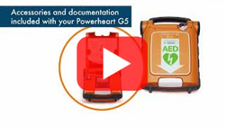 Unboxing of the Powerheart G5 AED with included accessories, documentation, and AED device with protective casing.