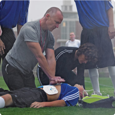Zoll AED Plus Lay Responder Defibrillator being used on a collapsed footballer