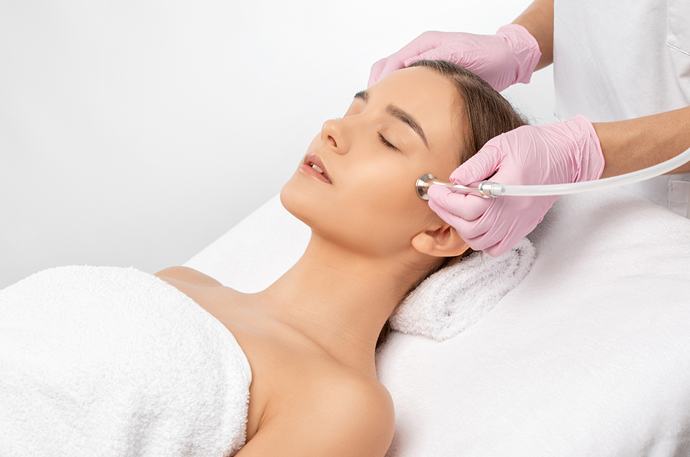 Clinician wearing pink gloves performing a facial treatment on a woman
