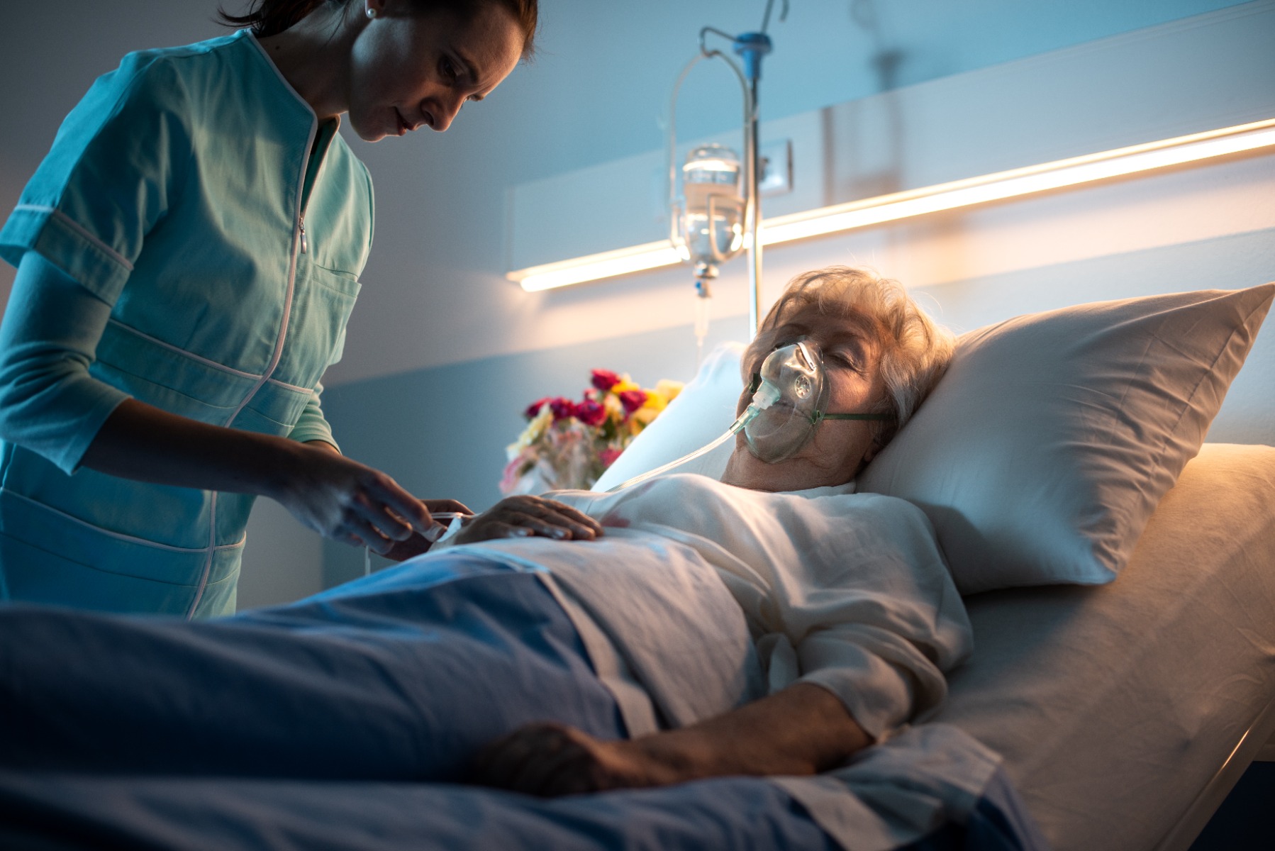 nurse taking care of patient in hospital bed
