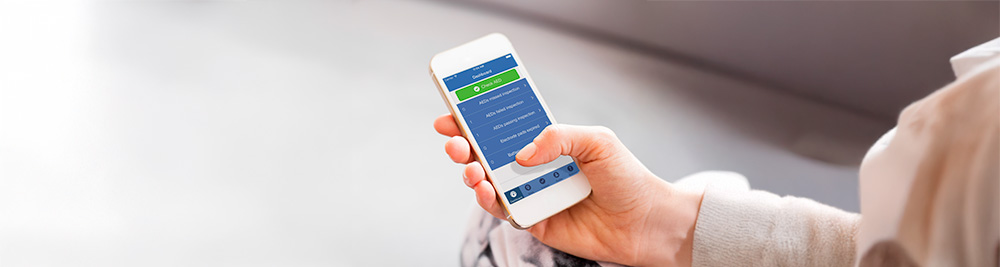Person using the PlusTrac AED management app on a smartphone, displaying device readiness and maintenance schedules.