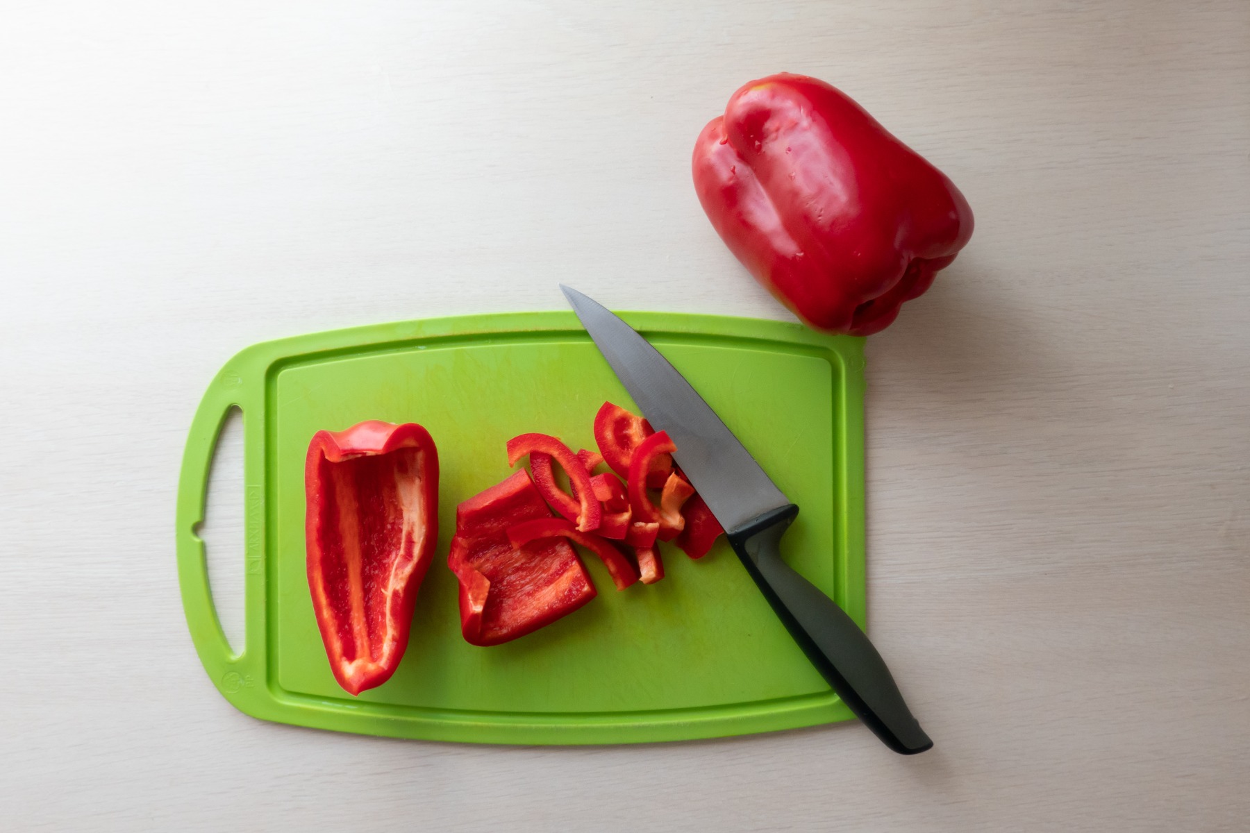 Chef knives and red pepper on green chopping board