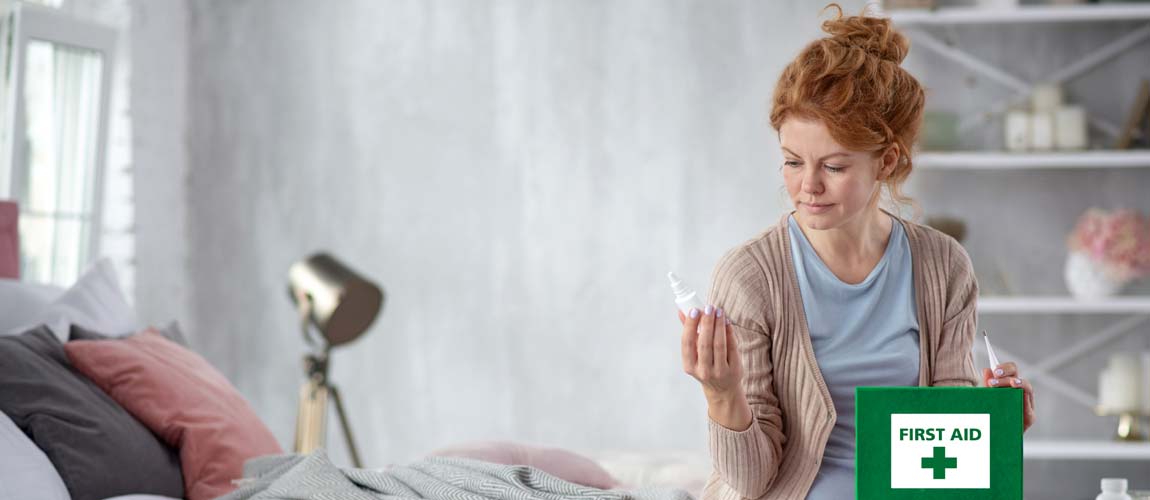 Woman looking through first aid box on bed