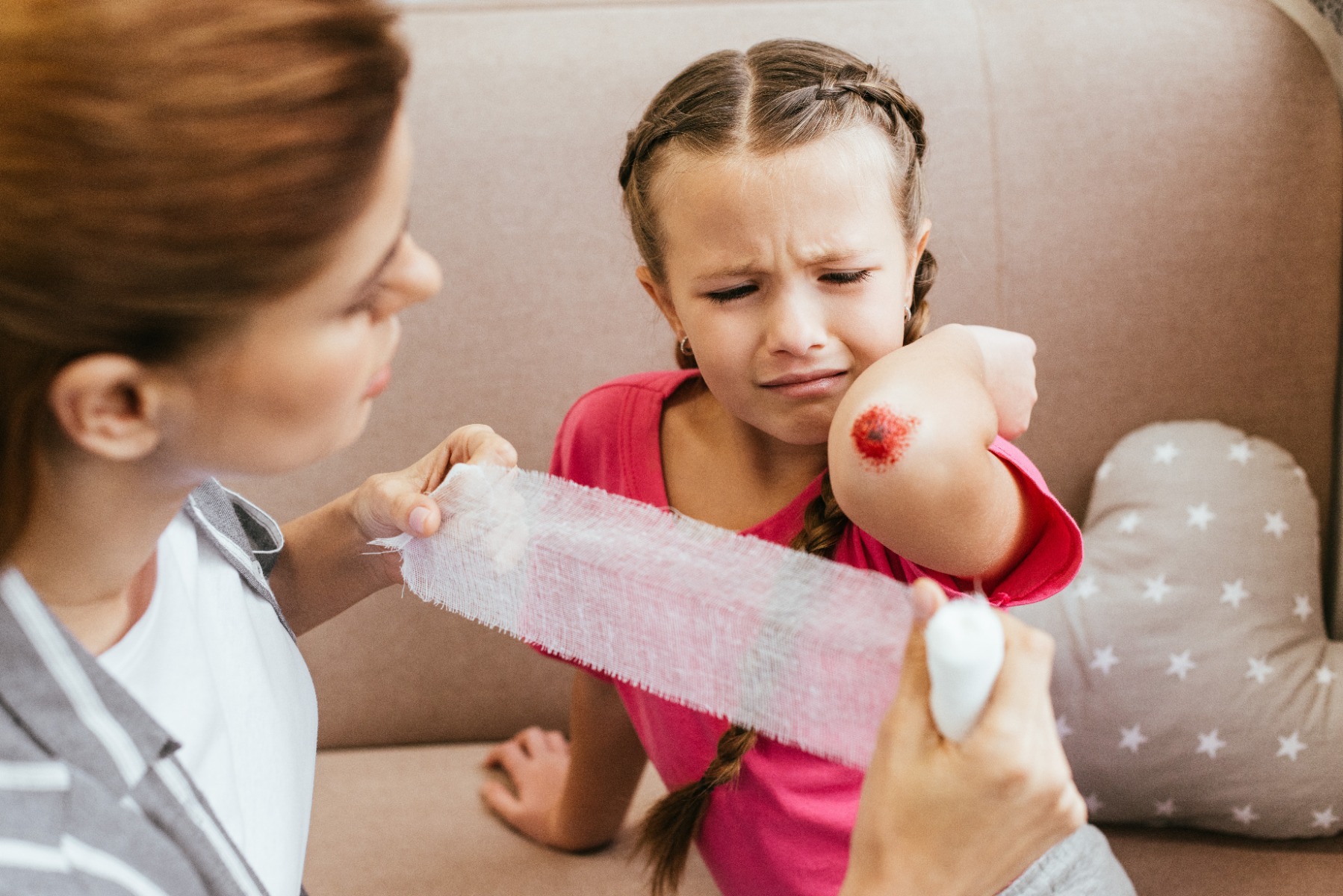 worried mother wounding bandage around elbow of crying daughter