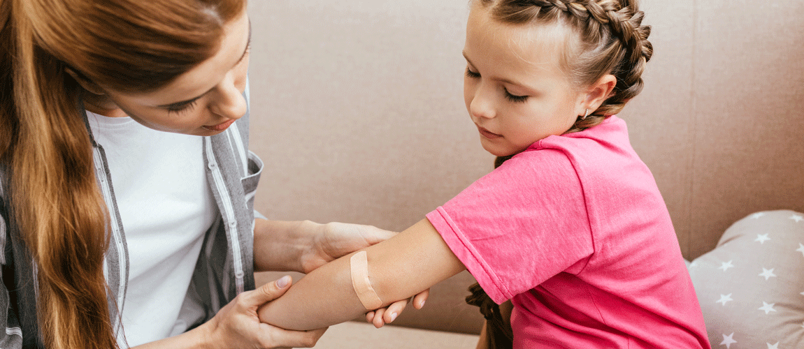 worried mother applying plaster on elbow of daughter